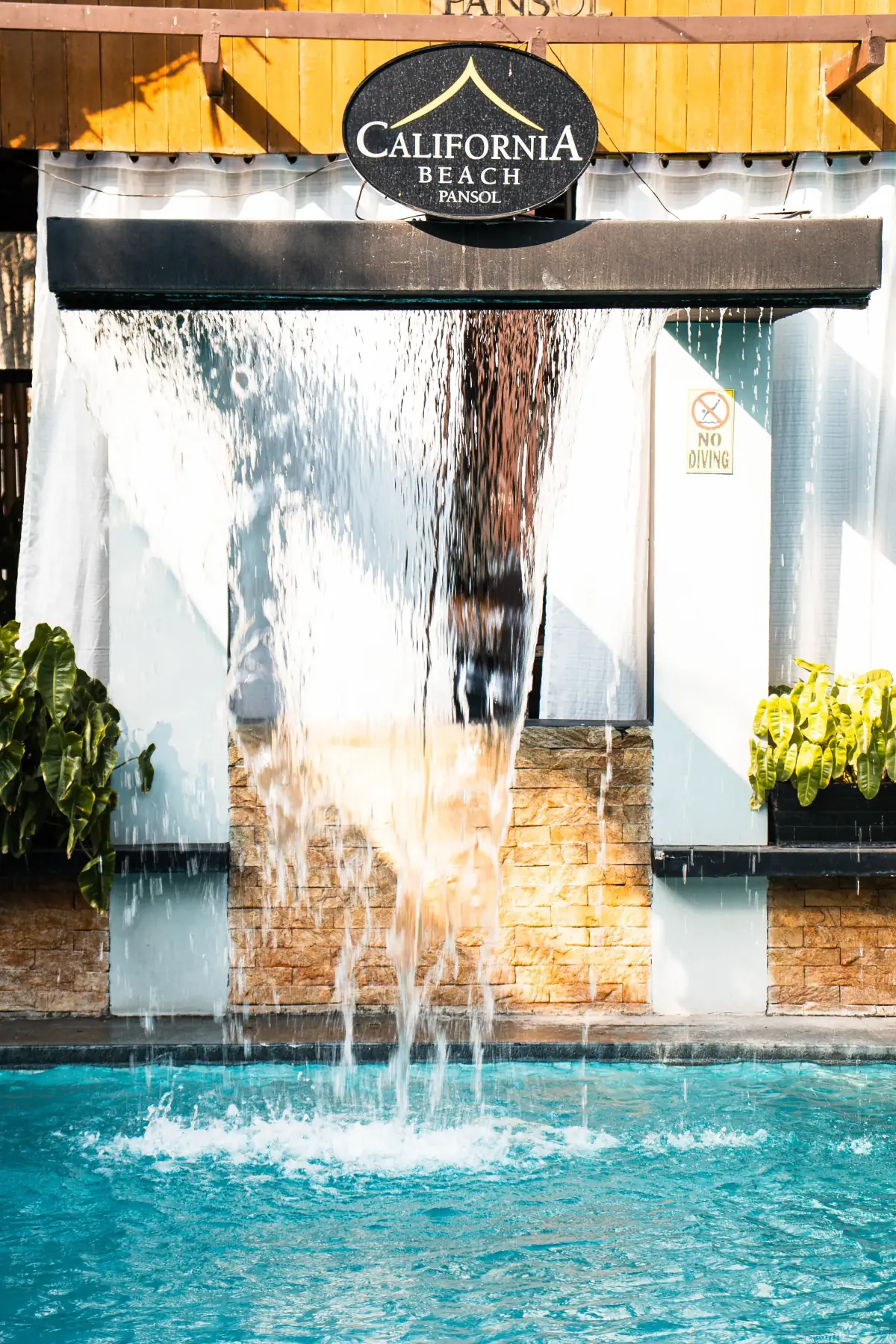 Villa 2 — waterfall sheet falling into the private pool below the brand sign